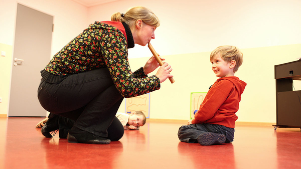 Musiklehrerin spielt Vorschulkind auf Blockflöte vor
