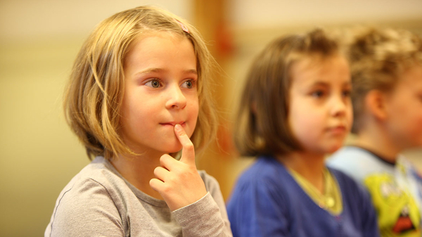 Drei Kinder lauschen aufmerksam im musikalischen Frühunterricht