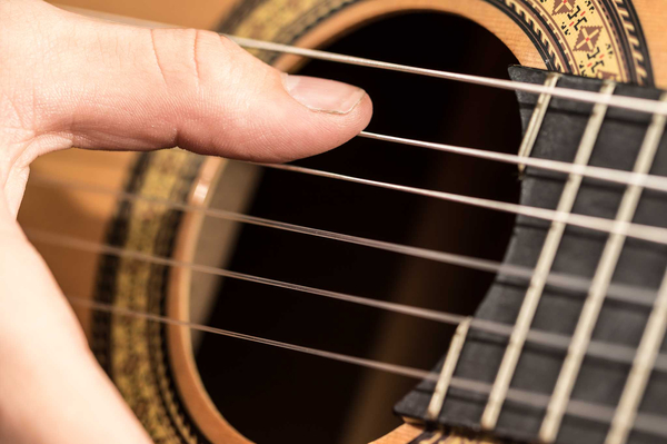 Spielhand am Schallloch einer Gitarre