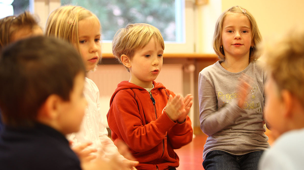 Kinder singen und klatschen im Stuhlkreis